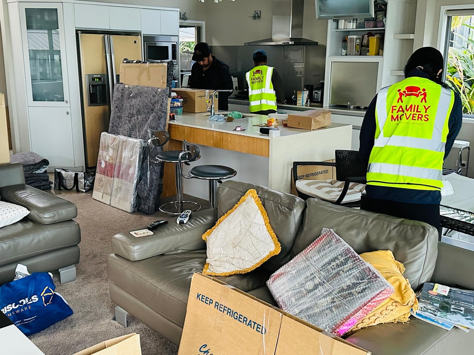Family Movers crew in branded hi-vis vests packing up a living room